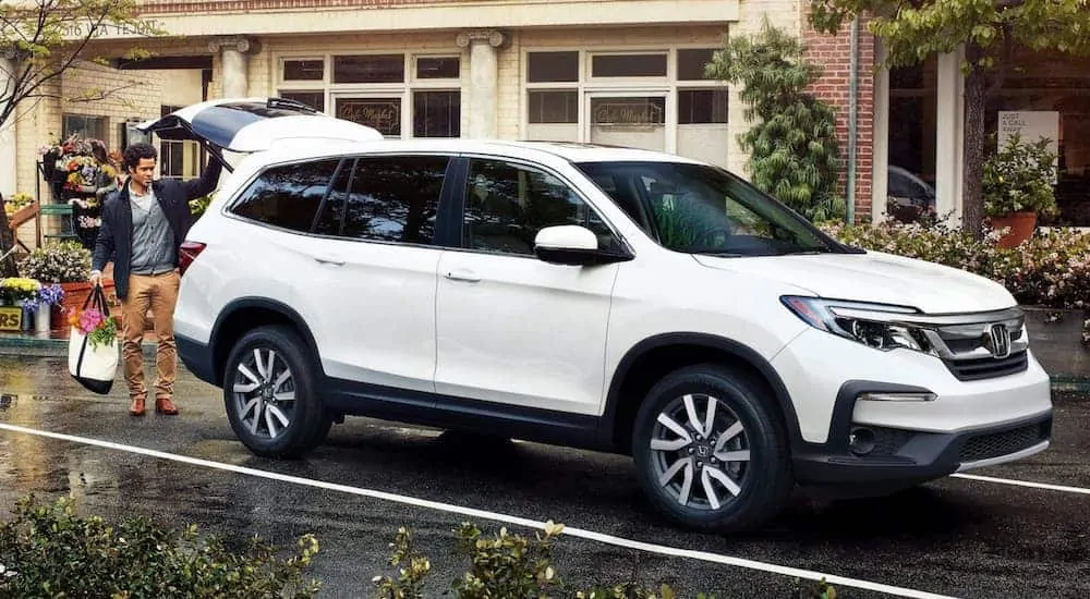 A man is loading flowers into a white 2020 Honda Pilot.