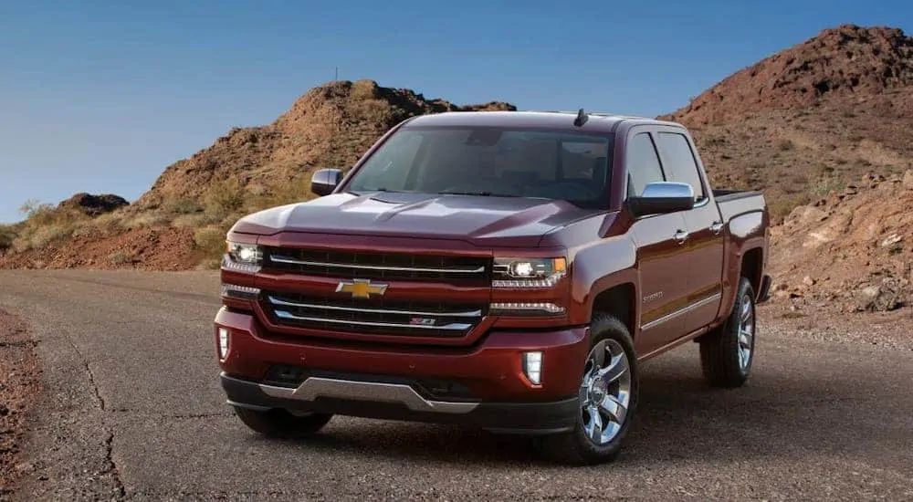 A red 2017 Chevy Silverado is parked on a desert highway.