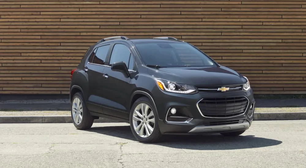 A black 2020 Chevy Trax is parked in front of a wooden wall.