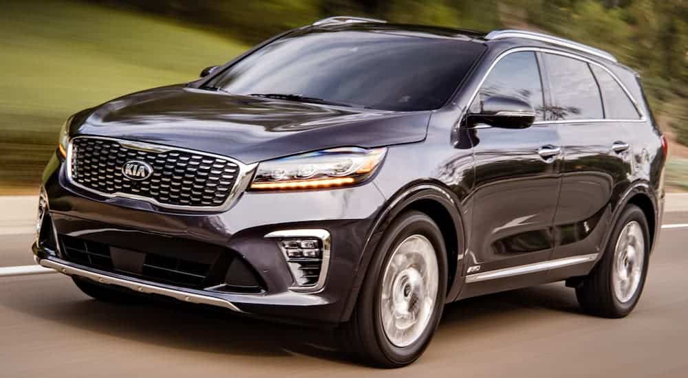 A black 2020 Kia Sorento is driving past blurred grass.