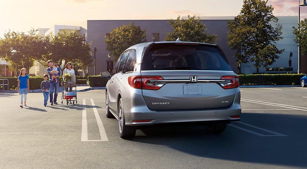 A family is walking towards a silver 2020 Honda Odyssey in a parking lot after winning the 2020 Honda Odyssey vs 2020 Toyota Sienna comparison.
