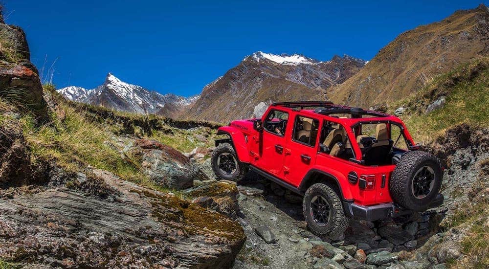 A red 2020 Jeep Wrangler Unlimited is climbing rocks during the 2020 Jeep Wrangler comparison.