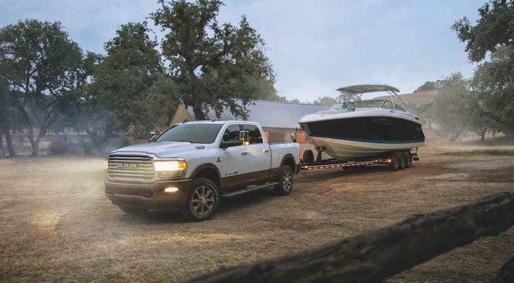 A white 2020 Ram 2500 is towing a boat on a ranch after winning the 2020 Ram 2500 vs 2020 Chevy Silverado 2500HD comparison.