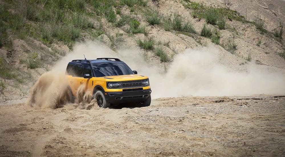 A yellow 2021 Ford Bronco Sport is kicking up sand.