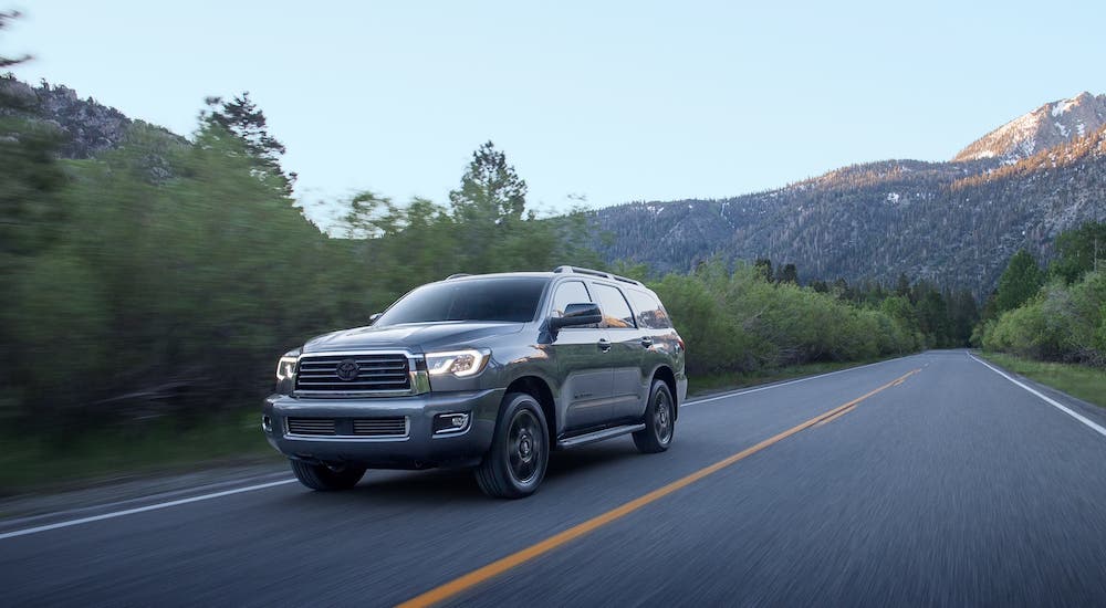 A gray 2020 Toyota Sequoia is driving on a rural highway.