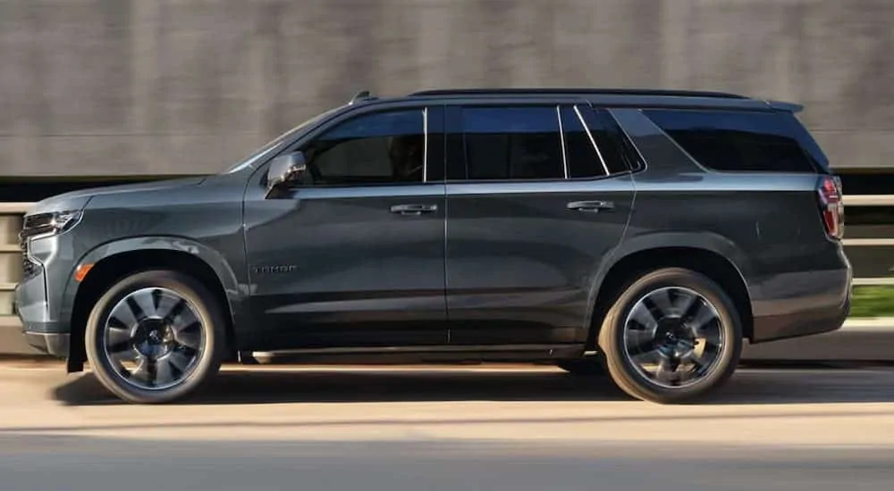 A grey 2021 Chevy Tahoe is shown from the side in front of a cement wall.