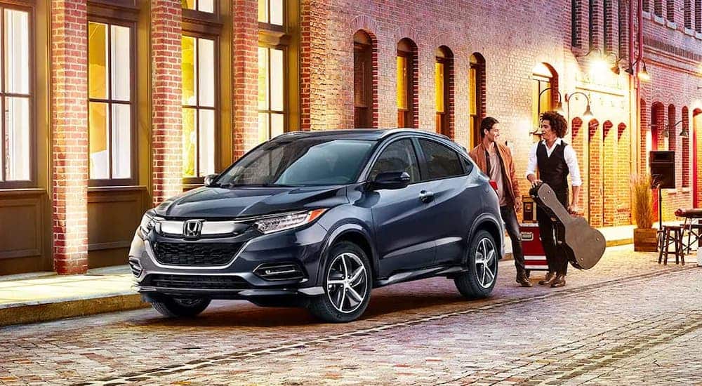 Two men are standing behind a gray 2020 Honda HR-V with a guitar.