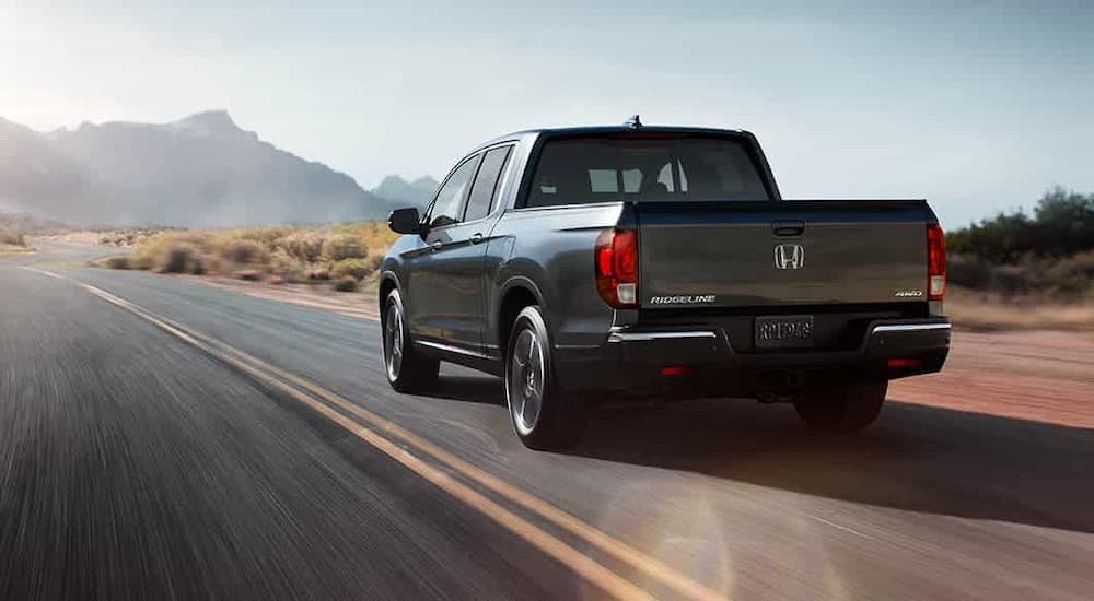 A gray 2020 Honda Ridgeline is driving away on a desert highway.