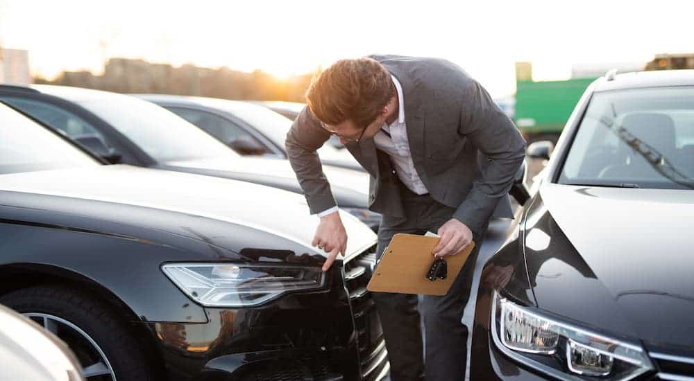 A car salesman is inspecting and cleaning a black car at a used car dealership near you.