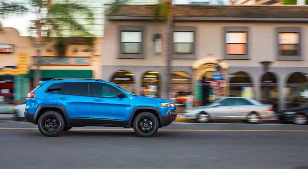 A blue 2020 Jeep Cherokee is shown from the side driving on a city street after losing the 2020 Chevy Blazer vs 2020 Jeep Cherokee comparison.