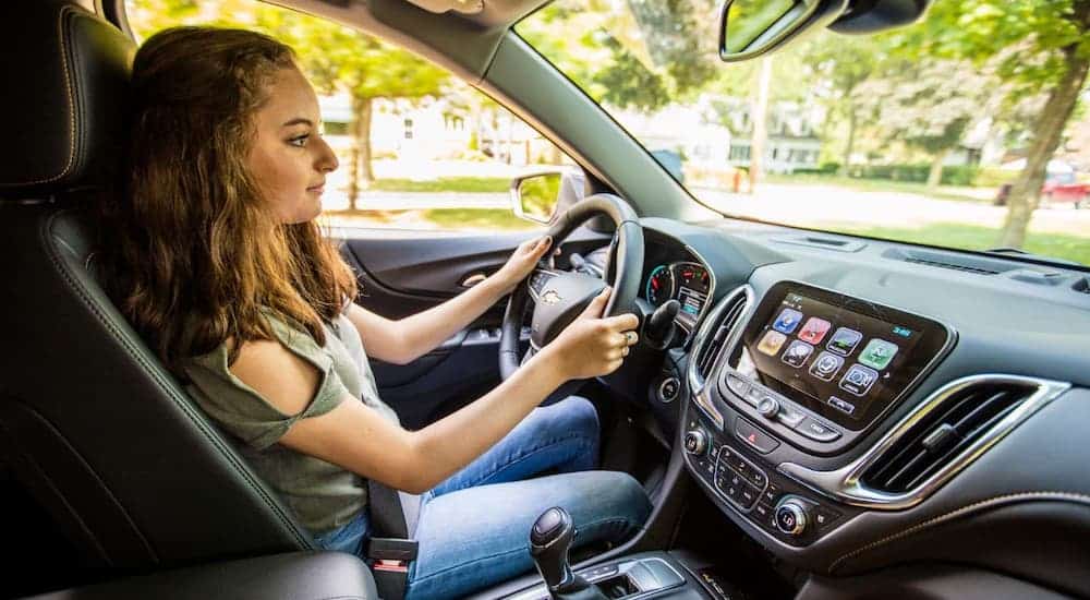 A teenager is shown from the passenger seat driving a 2020 Chevy Equinox.