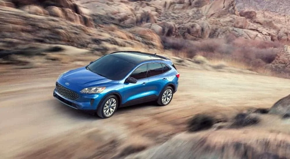A blue 2020 Ford Escape is driving on a dirt road and shown from a high angle after losing the 2020 Chevy Equinox vs 2020 Ford Escape comparison.
