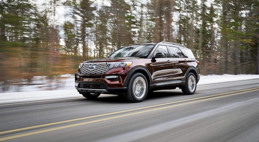 A burgundy 2020 Ford Explorer is driving on a snowy road after losing the 2020 Chevy Traverse vs 2020 Ford Explorer comparison.
