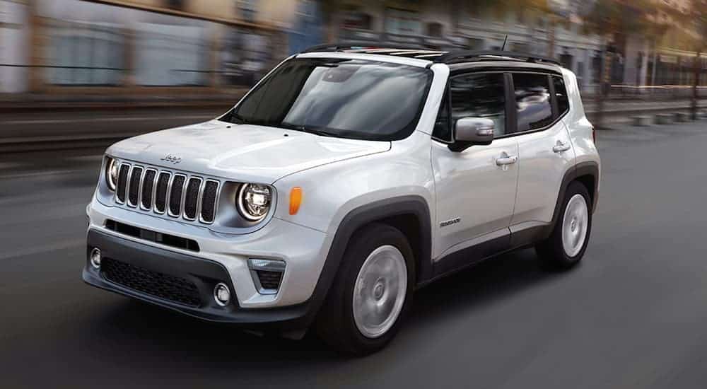 A white 2020 Jeep Renegade is driving on a city street.