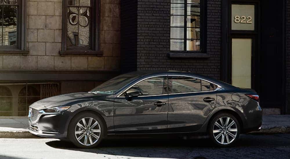 A grey 2020 Mazda 6 is parked on a city street in the shade.