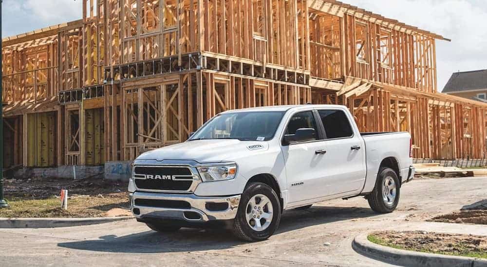 A white 2020 Ram 1500 Tradesman is leaving a construction site where a building is being framed.