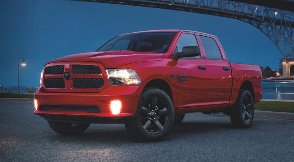 A red 2020 Ram 1500 Classic, which is similar when comparing the 2020 Ram 1500 vs 2020 Ram 1500 Classic, is parked under a bridge at night.