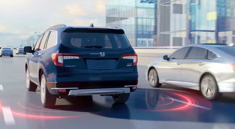 A blue 2021 Honda Pilot render is on a highway with red warning lines showing where the lanes are.