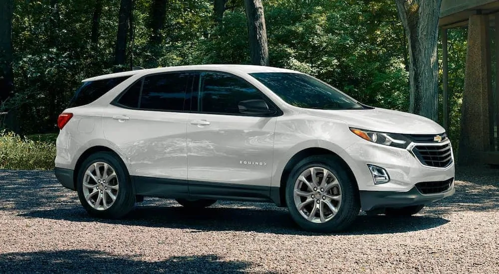 A white 2020 Chevy Equinox is parked on a gravel driveway in the woods.
