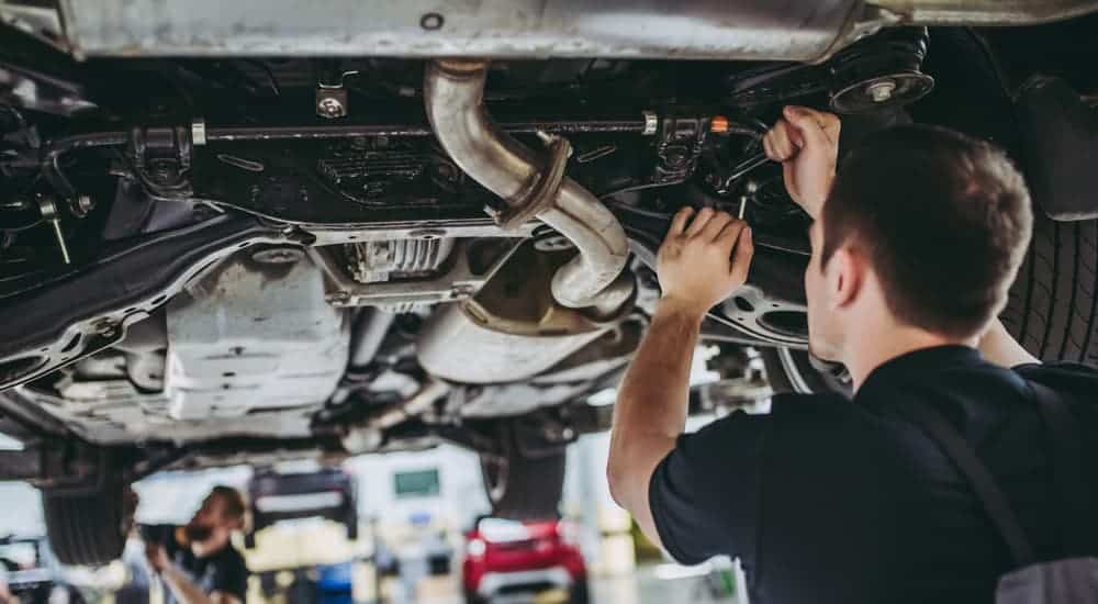 Two mechanics are working under a car.