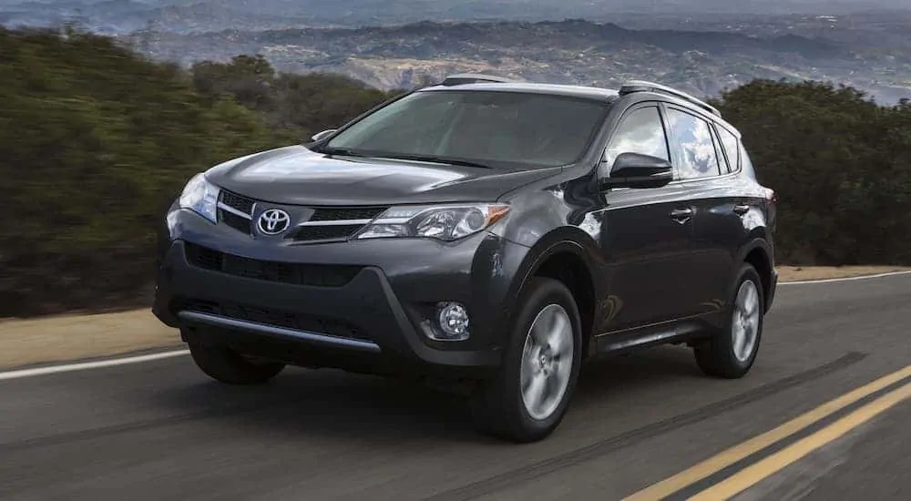 A gray 2015 Toyota RAV4 is driving on a mountain highway.