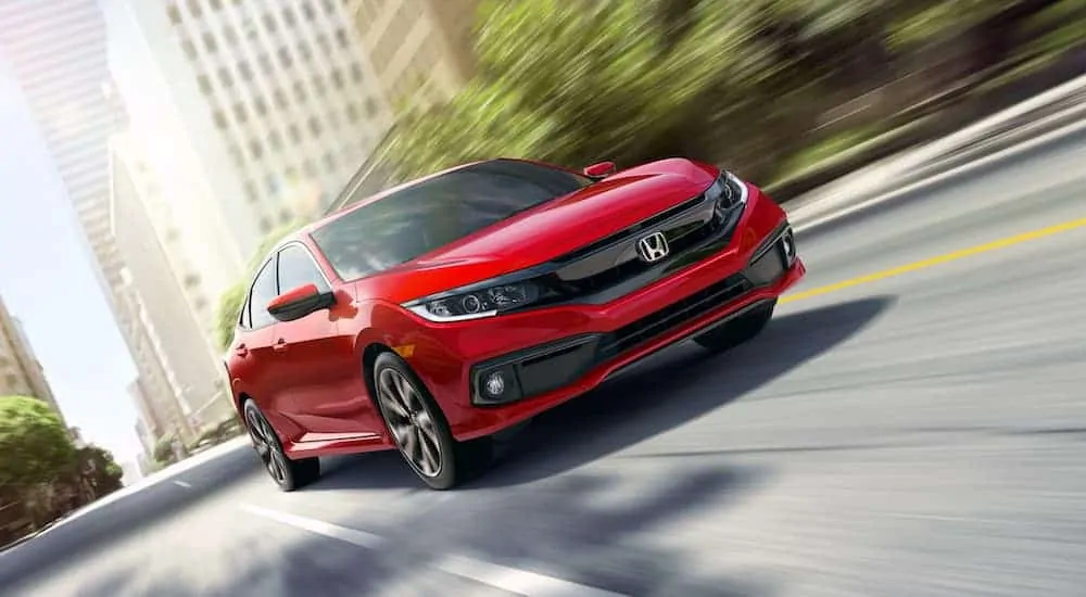 A red 2019 Honda Civic is driving on a city street.