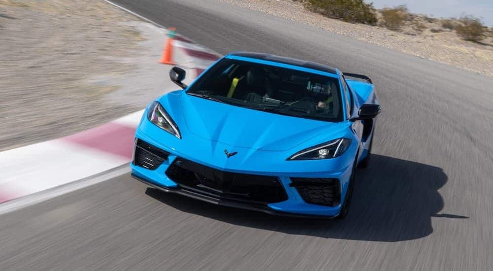 A bright blue 2020 Chevrolet Corvette Stingray is speeding around a race track.