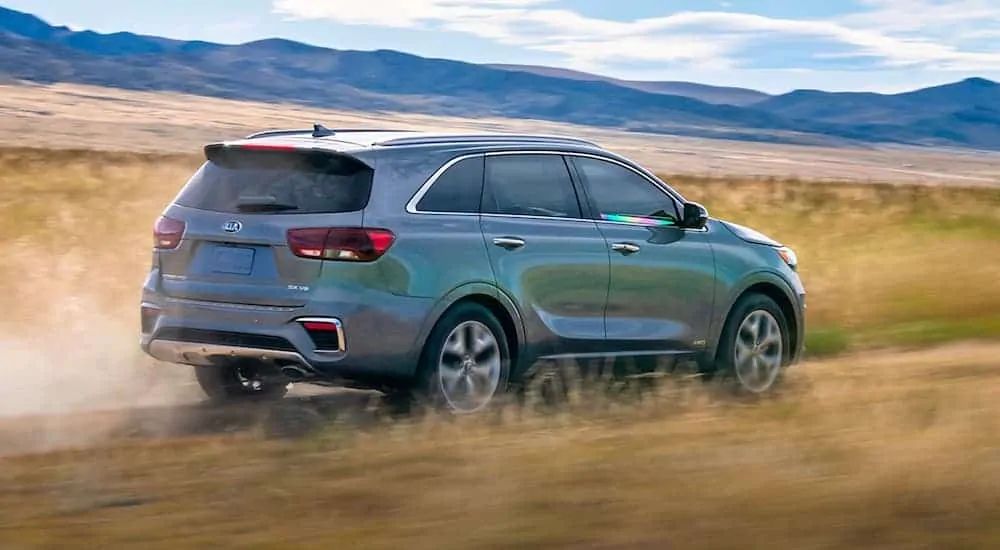 A silver 2020 Kia Sorento is driving away through a field after losing the 2020 Chevy Equinox vs 2020 Kia Sorento comparison.