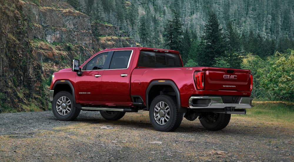 A red 2020 GMC Sierra 2500 is parked in front of pine trees after winning the 2020 GMC Sierra 2500 vs 2020 Chevy Silverado 2500 comparison.
