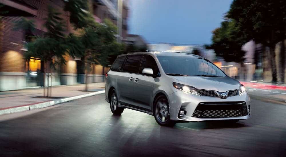 A silver 2020 Toyota Sienna is shown on a city street at night.