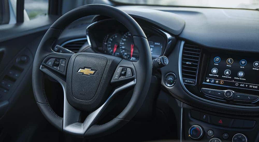 The front interior of the 2021 Chevorlet Trax is showing both the steering wheel and infotainment system.