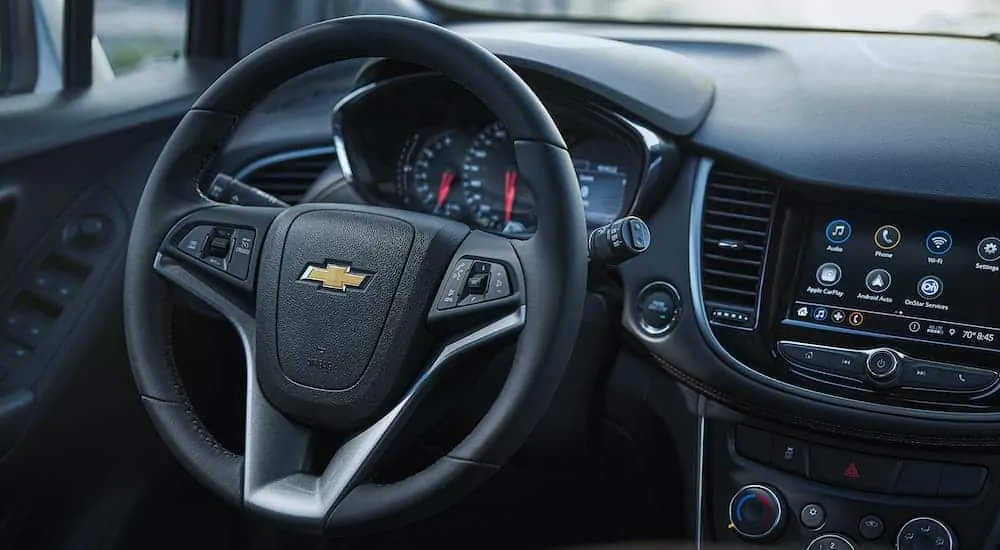 The front interior of the 2021 Chevorlet Trax is showing both the steering wheel and infotainment system.