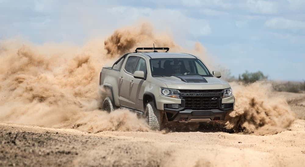A pale green 2021 Chevrolet Colorado ZR2 that is driving in the desert kicking up dust everywhere.