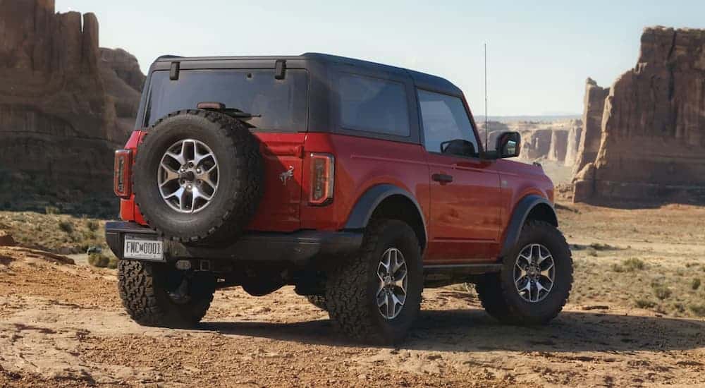 A red 2021 Ford Bronco 2dr is shown from the rear parked in from of desert rocks after winning the 2021 Ford Bronco (2dr) Vs 2020 Jeep Wrangler (2dr) comparison.