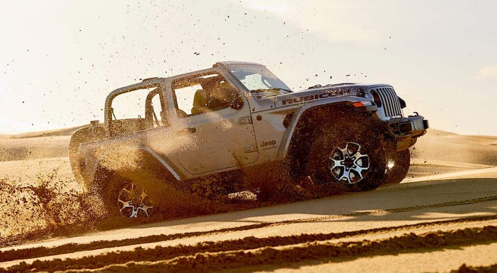 A silver 2020 Jeep Wrangler is off-roading on a sand dune.
