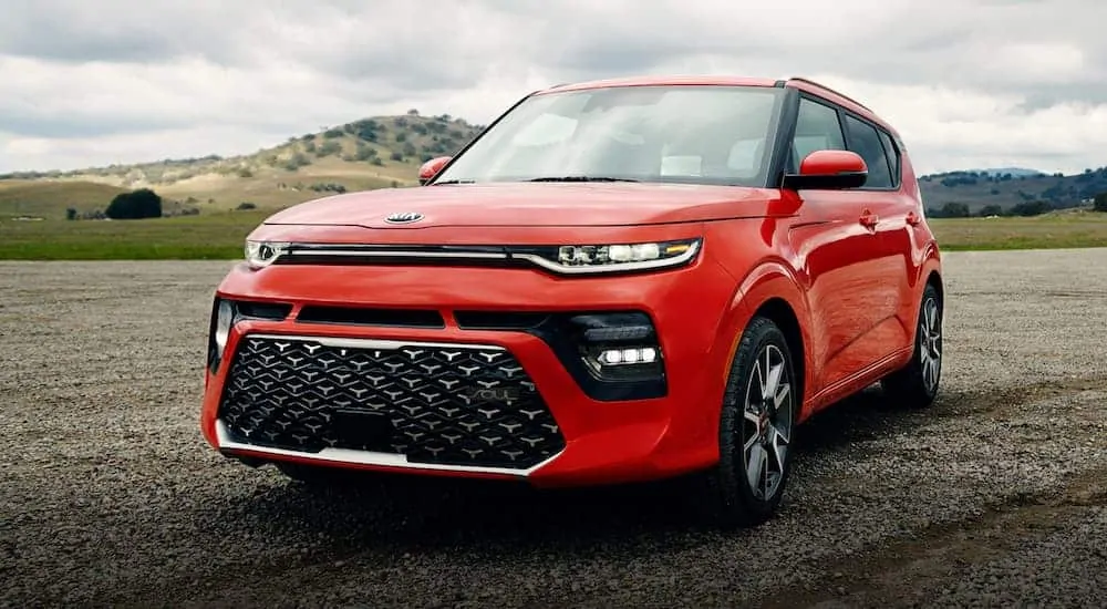 A red 2021 Kia Soul GT is parked in front of tree-covered hills.