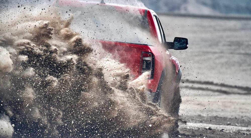 A red 2021 Ram 1500 TRX is shown from the rear kicking up sand while off-roading.