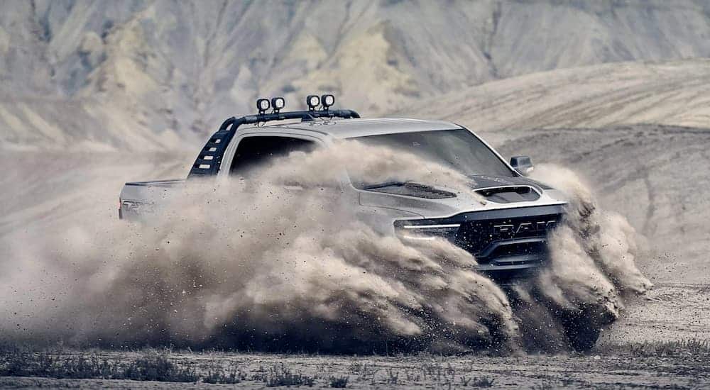 A silver 2021 Ram TRX is off-roading and kicking up sand.