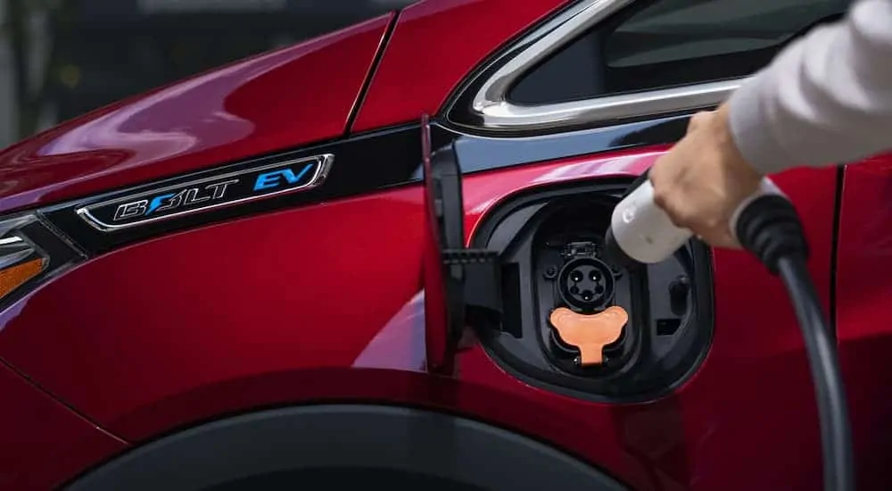 A closeup of the Chevy Bolt EV badging is shown on a red 2020 Bolt while it is charging.