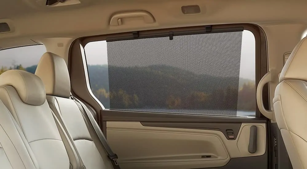 A window shade in the backseat of the tan interior of a 2020 Honda Odyssey EX is shown.