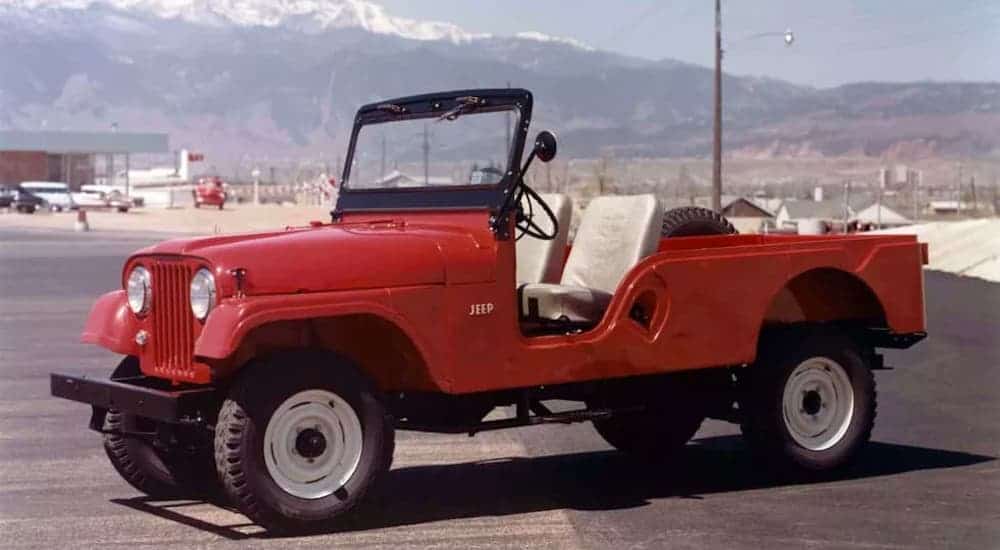 A classic to find at a Jeep dealership in Colorado Springs, CO, a red 1956 Jeep CJ-5, is shown on a runway.