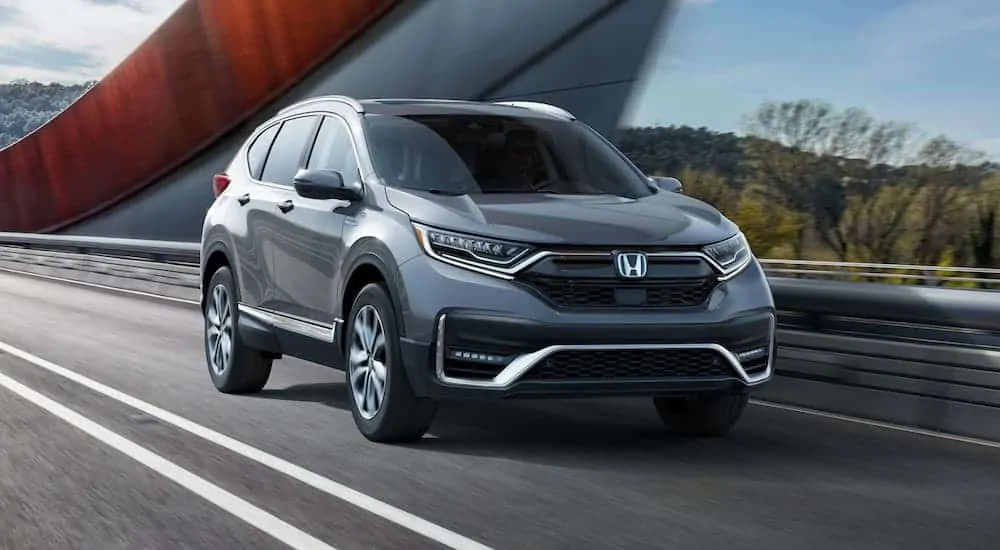 A silver 2020 Honda CR-V Touring is driving over a modern bridge.