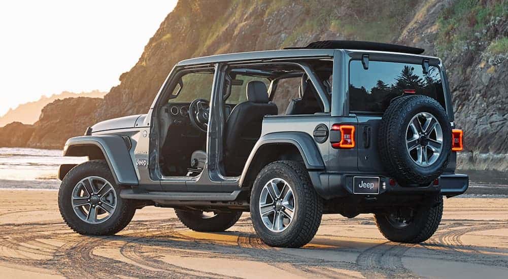 A grey 2020 Jeep Wrangler Unlimited with no doors is shown from the rear on the beach.