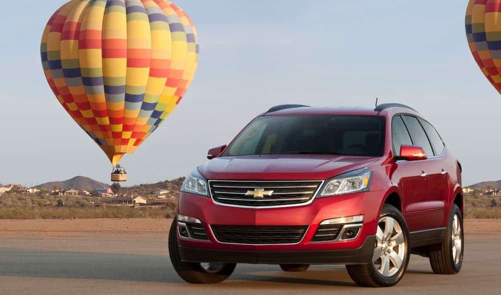 A red 2016 Used Chevy Traverse LTZ is parked in front of a multicolored hot air balloon.