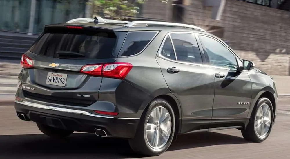 A dark grey 2020 Chevy Equinox is driving down the street.