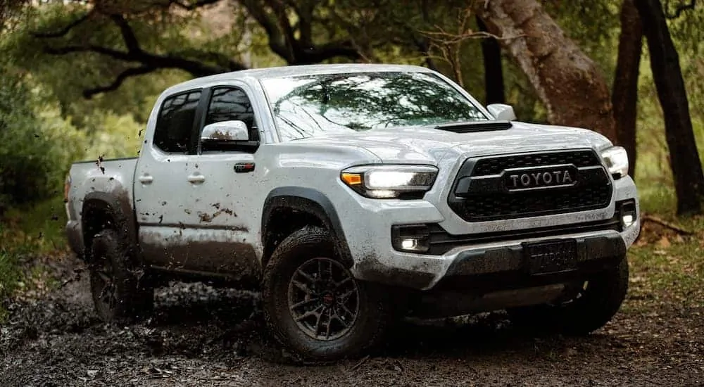 A white 2020 Toyota Tacoma TRD Pro is driving through the mud.