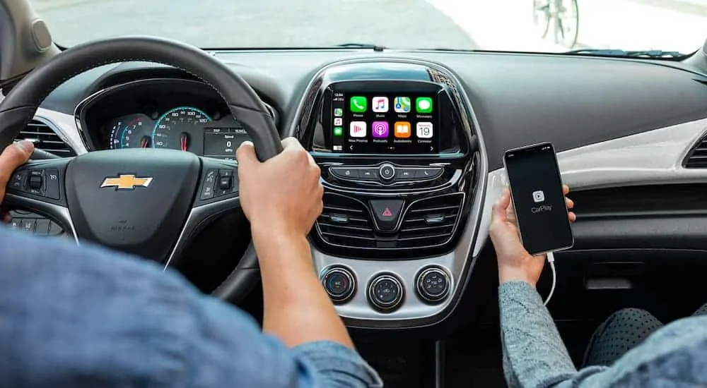 The infotainment system and a phone using car play is being shown on a 2021 Chevy Spark.
