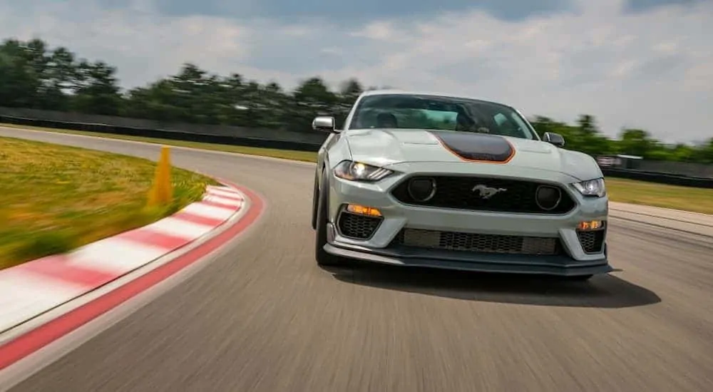 A white 2021 Ford Mustang Mach 1 is driving around the racetrack.