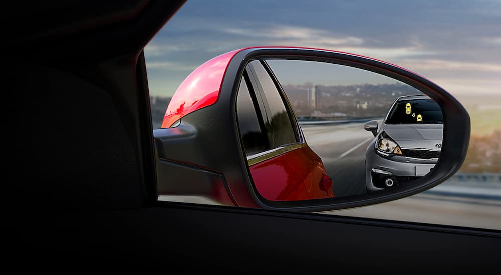 A close up is shown of the blind spot monitoring indicator on a red 2021 Kia Forte.