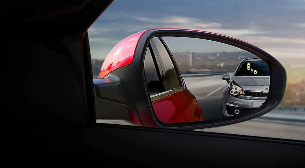 A close up is shown of the blind spot monitoring indicator on a red 2021 Kia Forte.